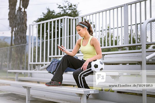 Soccer player using smartphone on bench