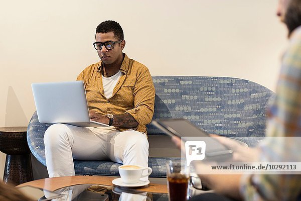 Junger Mann im Coffee-Shop mit Laptop