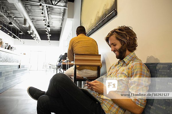 Young man sitting in coffee shop using smartphone