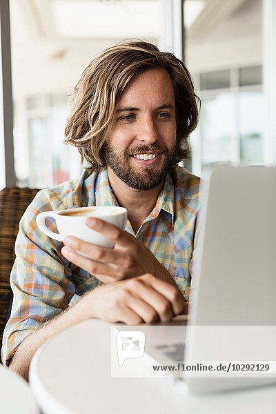 Mittlerer Erwachsener Mann im Coffee Shop Kaffee trinken mit Laptop