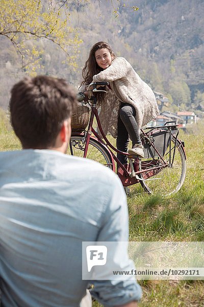 Über die Schulteransicht einer jungen Frau auf dem Fahrrad  die sich mit einem erwachsenen Mann unterhält.
