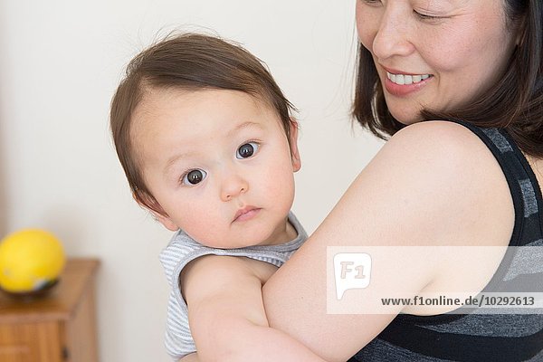 Portrait of cute baby boy in mature mothers arms