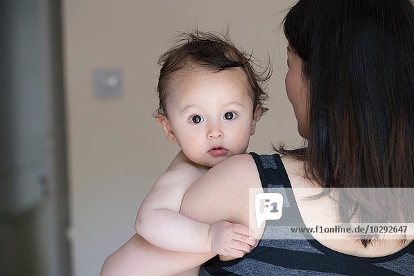 Portrait of curious baby boy in mature mothers arms