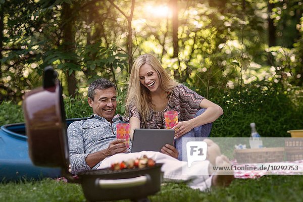 Erwachsener Mann und Freundin beim Picknickgrill auf dem digitalen Tablett
