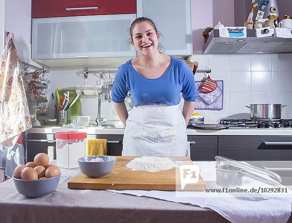 Porträt einer erwachsenen Frau bei der Zubereitung von Speisen in der Küche