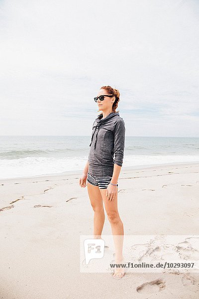 Mittlere erwachsene Frau am Strand stehend,  mit Blick auf die Aussicht