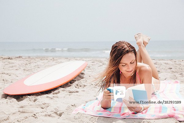 Mittlere erwachsene Frau am Strand liegend  Lesebuch