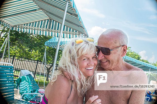 Porträt des liebevollen Seniorenpaares am Pool im Freien