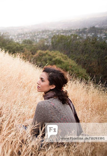 Young woman sitting gazing from long grass