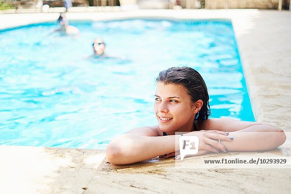 Portrait of teenage girl with wet hair looking away from swimming pool
