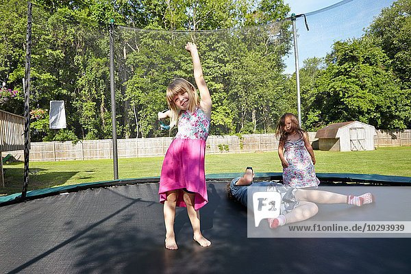 Drei Mädchen spielen auf dem Trampolin im Garten