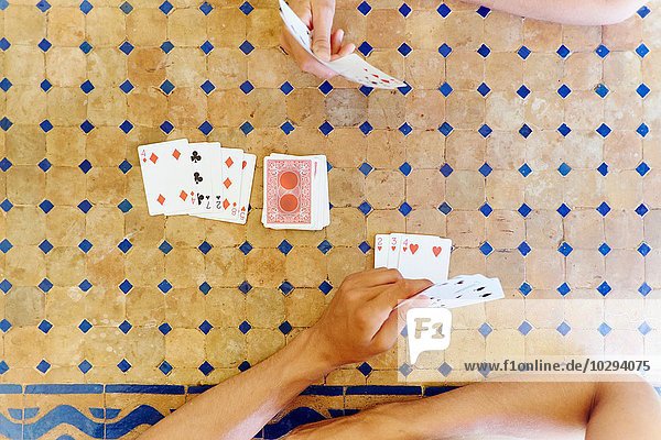 Overhead-Foto von reifer Frau und Sohn  die am Tisch Karten spielen.