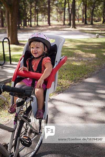 Young girl sitting in child's bicycle seat  enjoying journey