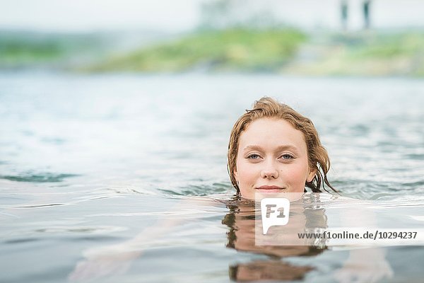Portrait of serene young woman swimming in Secret Lagoon hot spring (Gamla Laugin)  Fludir  Iceland