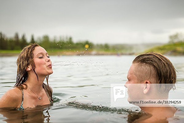 Young couple squirting water in Secret Lagoon hot spring (Gamla Laugin)  Fludir  Iceland