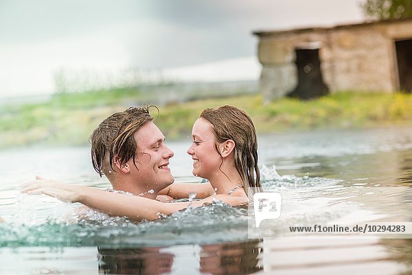 Romantic young couple splashing in Secret Lagoon hot spring (Gamla Laugin)  Fludir  Iceland