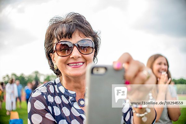 Mature woman taking photograph with smartphone