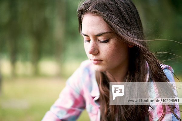Portrait of teenage girl looking downward in woodland
