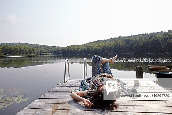 Woman relaxing on lake pier  New Milford  Pennsylvania  USA