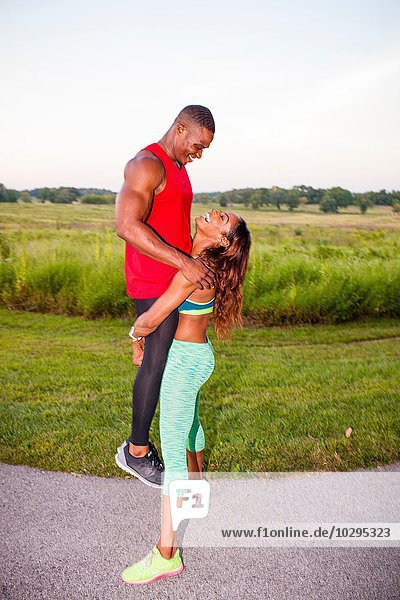 Young woman training by lifting up boyfriend