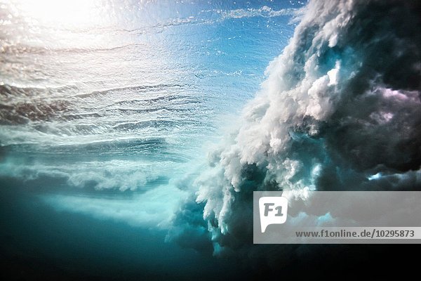 Unterwasseransicht einer riesigen Welle  die über ein flaches Riff stürzt.