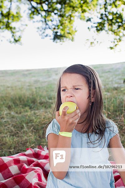 Mädchen isst grünen Apfel beim Park-Picknick