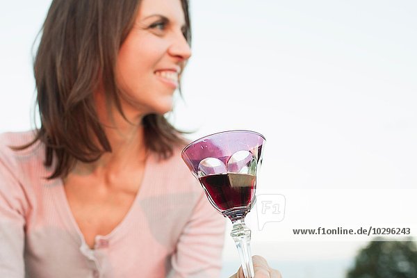 Reife Frau trinkt ein Glas Rotwein im Park