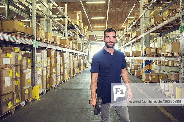 Portrait of male warehouse worker standing in distribution warehouse aisle