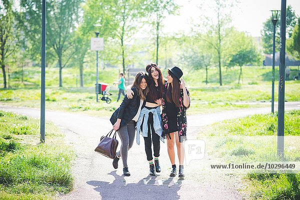 Three young female friends strolling together in park