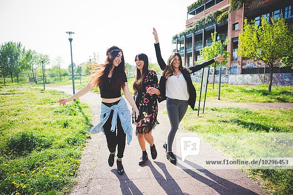 Three young female friends dancing together in park