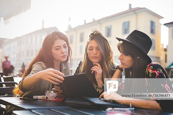 Drei junge Frauen lesen Update auf digitalen Tablette im Bürgersteig Cafe