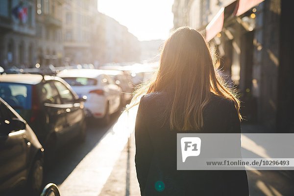Rückansicht der jungen Frau beim Spaziergang auf der Stadtstraße