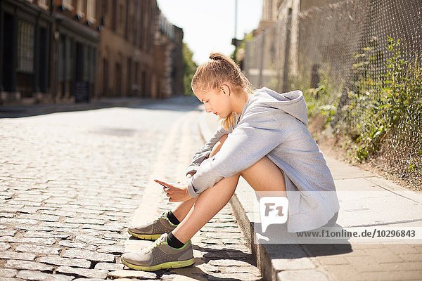 Runner using smartphone on pavement  Wapping  London