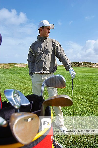 Golfer hält Golfschläger  Hand in Hand  schaut weg