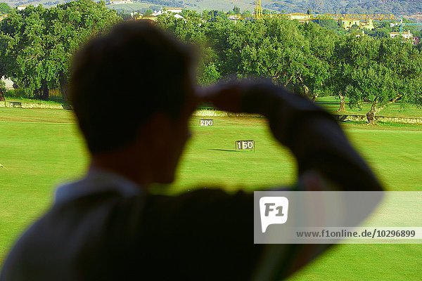 Rückansicht des mittleren Erwachsenen  der die Augen abschirmt und auf den Golfplatz schaut  Fokus auf den Hintergrund.