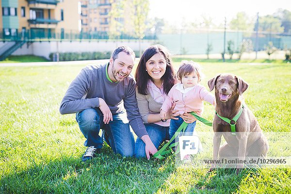 Porträt eines erwachsenen Paares mit Kleinkind Tochter und Hund im Park
