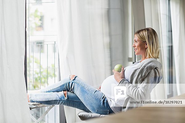 Vollzeitschwangerschaft junge Frau beim Apfelessen