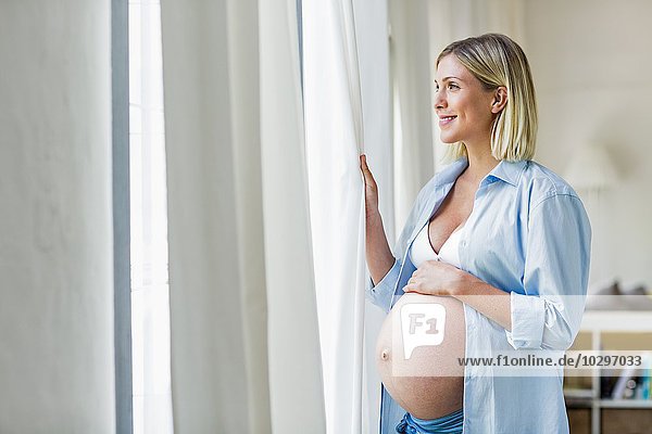 Vollzeitschwangerschaft junge Frau mit Blick aus dem Fenster