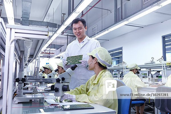 Supervisor overseeing quality check station at factory producing flexible electronic circuit boards. Plant is located in the south of China  in Zhuhai  Guangdong province