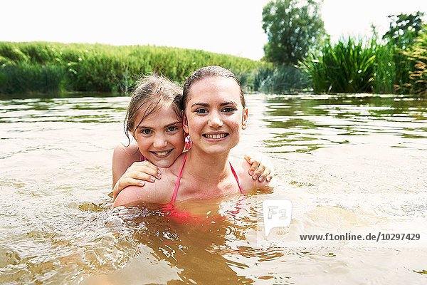 Porträt eines Mädchens und einer Schwester  die im See schwimmen.