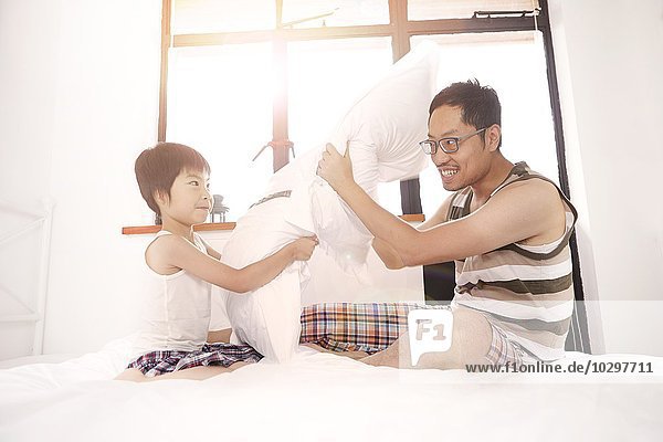 Chinese father and son having a pillow fight