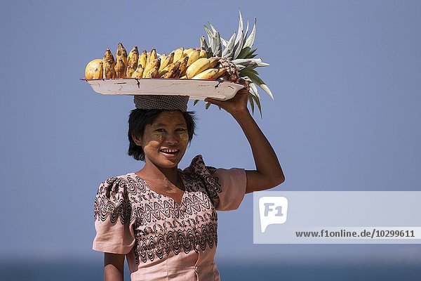 Native woman with a bowl of bananas on her head and Thanaka paste on her face  selling bananas on the beach of Ngapali Beach  Thandwe  Rakhine State  Myanmar  Asia
