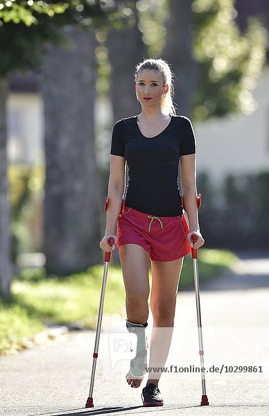 Junge Frau mit Krücken  Gehhilfe bei Verletzung am Fuß  mit Gipsschiene  Deutschland  Europa