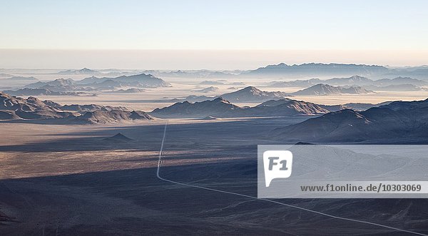 Isolierte Bergrücken und die C27 Schotterstraße  am Rande der Namib-Wüste  Küstennebel hinten  Luftbild  Namibrand-Naturreservat  Namibia  Afrika