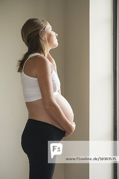 Pregnant woman looking at view through window