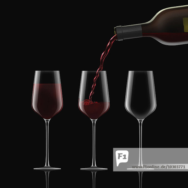Rotwein wird in drei Gläser gegossen
