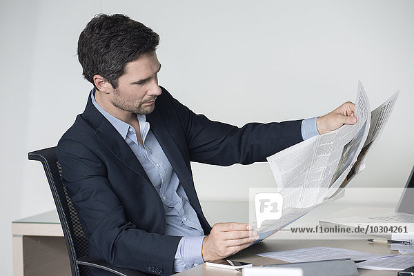 Geschäftsmann liest Zeitung im Büro
