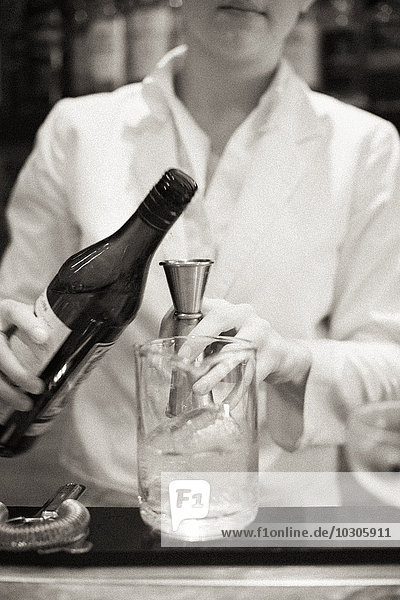 Eine junge Frau mixt einen Cocktail  eine Mixologin bei der Arbeit.