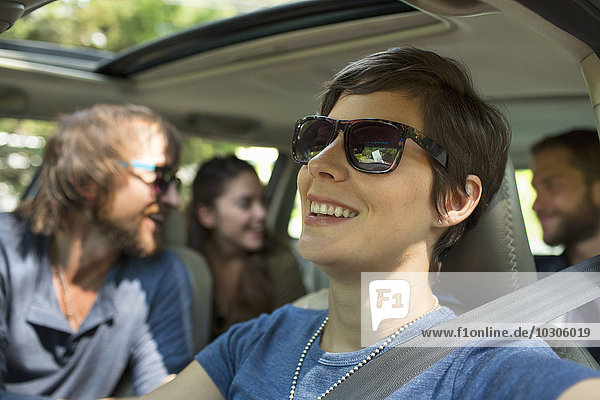 A group of people inside a car  on a road trip. View to the back seat  four passengers.