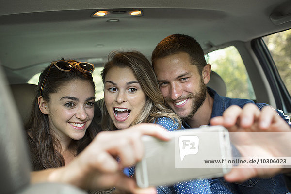 Eine Gruppe von Menschen in einem Auto  zwei Frauen und ein Mann  die ein Selfy nehmen.